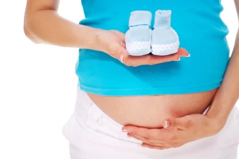 Close-up of pregnant woman holding blue baby bootees in hand against white backg Stock Photos