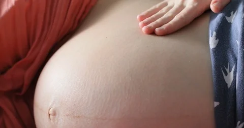 Close up pregnant woman playing with baby kicking from inside the womb belly Stock Footage