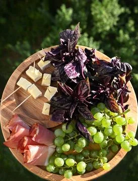 Close-up of a premium appetizer platter featuring prosciutto, cheese, and grapes Fotos Stock