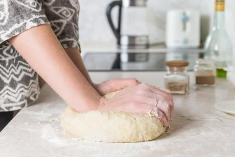 Close-up of preparing and mixing the dough. Female hands kneading dough in mo Stock Photos