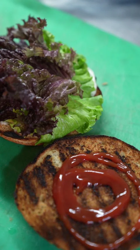 Close-up of preparing gourmet vegan burger with fresh lettuce and sauce Stock-Footage 340368140