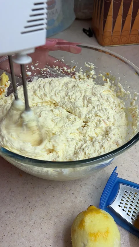 Close-up preparing homemade lemon cake batter using an electric hand mixer in a Stock Footage 346690496