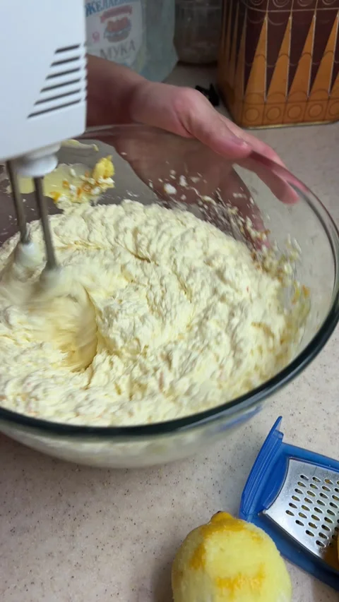 Close-up preparing homemade lemon cake batter using an electric hand mixer in a Stock Footage 346691686