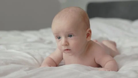 Close up of pretty infant lying on bed on his stomach Stock Footage 180597732
