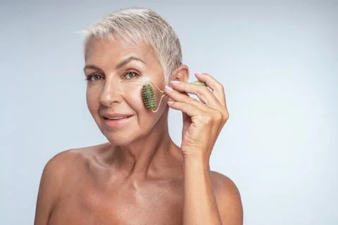 Close up of a pretty lady using jade roller on her cheek Stock-Fotos