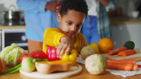 Close-up of pretty nice kid sorting vegetables on table. Family is cooking Video stock 147270869