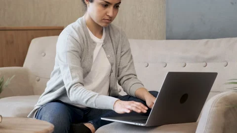 Close up Pretty young lady sitting on couch at home, using laptop Stock Footage 158236789