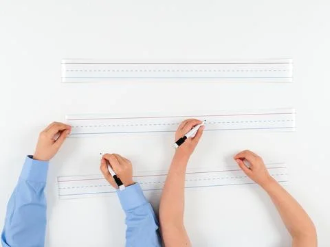 Close-Up of Primary School Students' Hands Writing on Lined Paper Stock Photos