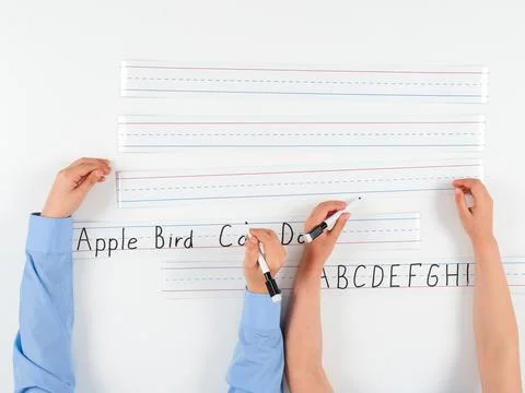 Close-Up of Primary School Students' Hands Writing on Lined Paper Stock Photos
