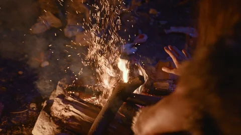 Close-up of primitive homo sapiens warming up hands and cooking animal bone on Stock Footage 116631365