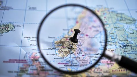 Close-up of a printed map with a magnifying glass highlighting Oslo Stock Photos