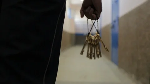 Close-up of prison keys hold by a guard and walking through a prison Stock Footage