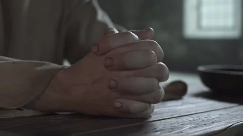 Close up of prisoner hands folded in prayer inside a dark dungeon cell 스톡 동영상 338990191
