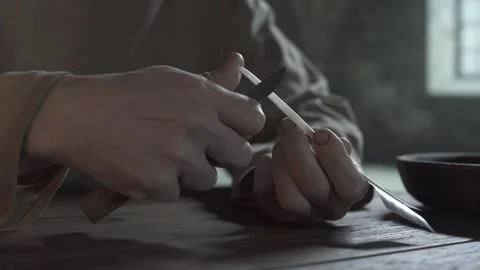 Close up of prisoner hands making a scoop cut on a quill inside a dungeon Stock Footage 337929624