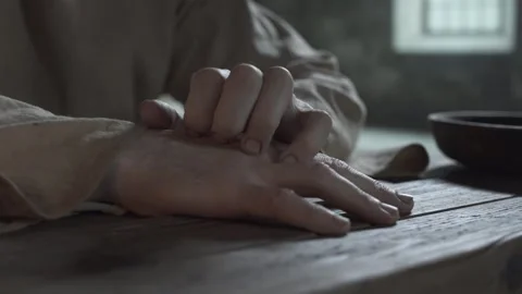 Close up of prisoner hands scratching an arm on a wooden table 스톡 동영상 338991415