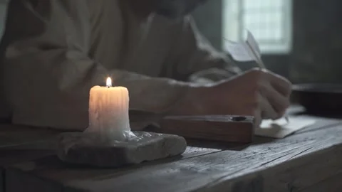 Close up of prisoner hands writing on parchment near a candle, camera tracking 스톡 동영상 338991019