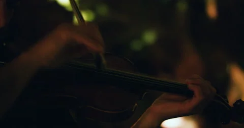 Close up of pro surfer Nuno Santos playing violin in front of light up wall Stock Footage 155257426