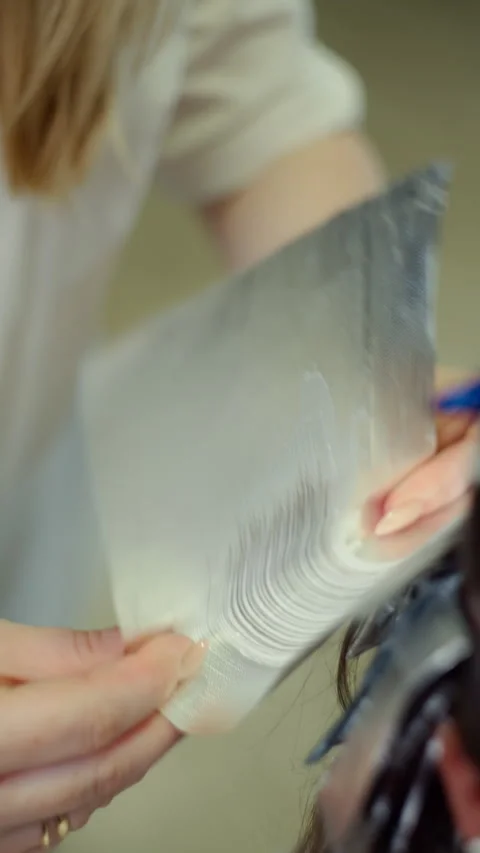 Close up process of applying dye to woman hair as hairdresser wraps each Video stock 336127057