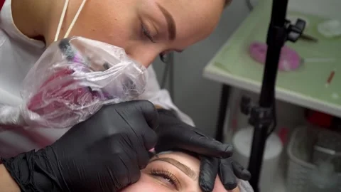 Close up process of applying permanent makeup tattoo on eyebrows woman in Stock Footage 242530505