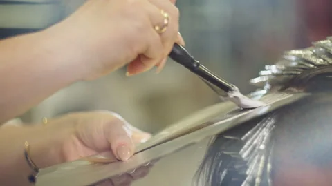 Close up process of bleaching and dyeing woman hair by professional stylist 스톡 동영상 318187047