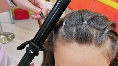 Close-up process of curling long brown hair with a black conical wand 2 Stock Footage 326483610