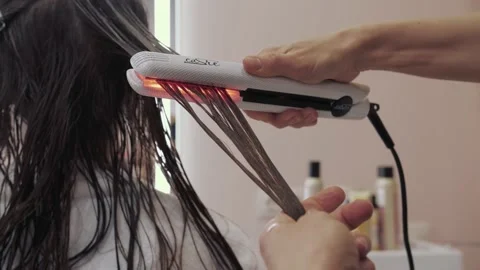 Close-up of the process of diagnosing and treating a girl's long brown hair for Stock Footage 155740008
