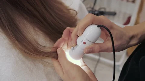 Close-up of the process of diagnosing and treating a girl's long brown hair for Stock Footage 155740100
