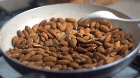 Close up, the process of frying and stirring almonds nuts in a pan on the stove, Stock Footage 107867674