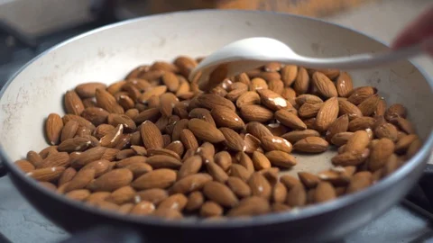 Close up, the process of frying and stirring almonds nuts in a pan on the stove, Stock Footage 107868161