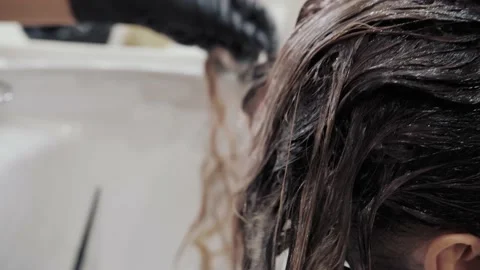 Close-up of the process of highlighting and washing a girl's long brown hair for Stock Footage 155741574