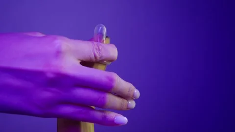 A close-up of the process of putting a condom on a banana, using lubricant. Stock Footage 308399744