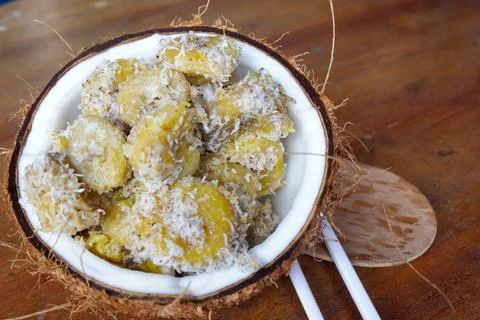 Close up of processed bananas are placed in old coconuts on brown table Stock Photos