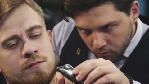 Close up of a professional barber trimming beard of a young man Stock Footage 311528035