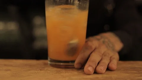 Close Up Of Professional Bartender Stirring Orange Drink with Bar Spoon Stock Footage 129781376