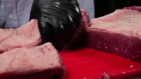 Close-up of Professional Butcher Slicing Raw Beef Steak on Red Cutting Board Stock Footage 331635040
