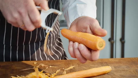 Close-up of a professional chef peeling a carrot with a vegetable peeler. Stock Footage 304794103