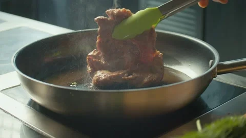 Close up. Professional Chef Turns Over with Tongs Piece of Meat Frying on a Pan. Stock Footage 196258580