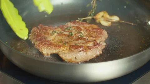 Close up. Professional Chef Turns Over with Tongs Piece of Meat Frying on a Pan. Stock Footage 196258893