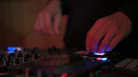 Close up of a professional disc jockey's hands manipulating knobs, faders, and Stock-Footage 327684447