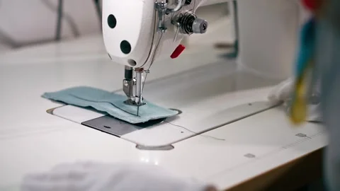 Close up professional dry cleaner young girl hems a patch on a sweater with a Video stock 277166633