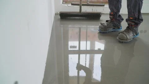 Close up on professional flooring installation. Builder spreading gray epoxy  Stock Photos