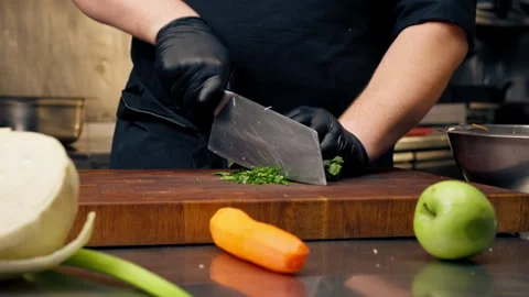 Close up in a professional kitchen chef in a black jacket and gloves chops Stock Footage 276298568
