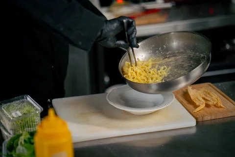 Close-up in a professional kitchen chef in black gloves prepares pasta stages of 스톡 사진
