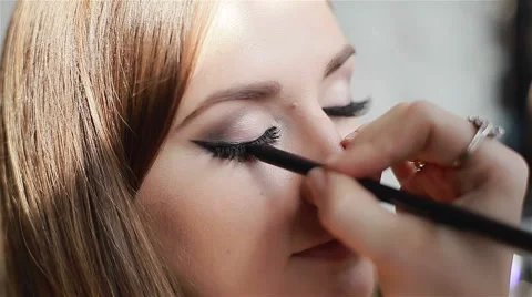 Close-up of professional make-up artist applying eyeliner on eyelid Stock Footage 52993205