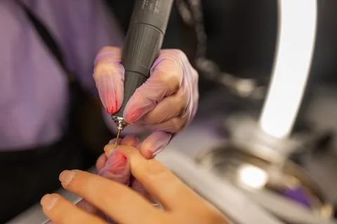 Close up of professional manicure procedure using electric nail drill. Nail Stock Photos