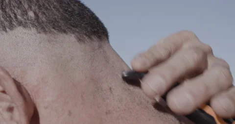 Close up of professional surfer David Langer shaving his hair off outside Stock Footage 160120223