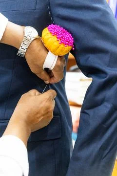 Close-up of professional tailor adjusting and refining new suit with needles to Stock Photos