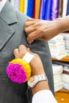 Close-up of professional tailor adjusting and refining new suit with needles to Stock Photos