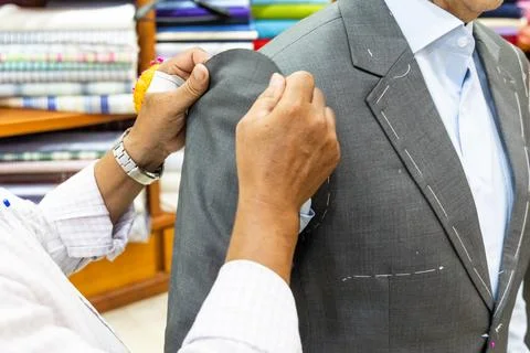 Close-up of professional tailor adjusting and refining new suit with needles to Stock Photos