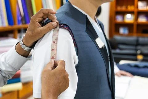 Close-up of professional tailor measuring client body with measuring tape to Stock Photos